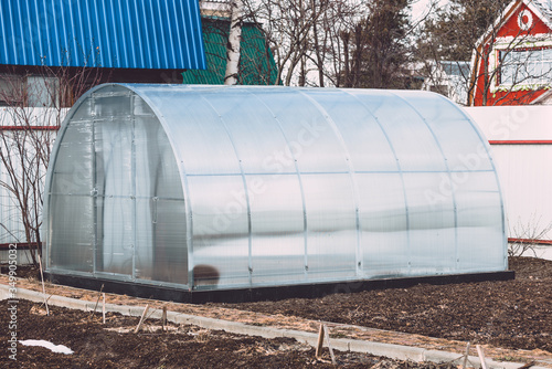 Greenhouse for growing flowers and vegetables from polycarbonate installed in garden.