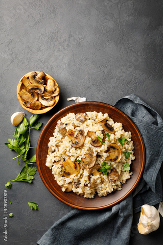 A dish of Italian cuisine - risotto from rice and mushrooms in a brown plate on a black slate background. Top view. Flat lay. Copy space. photo