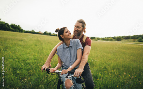 Happy couple enjoying in their love and riding bicycle in nature