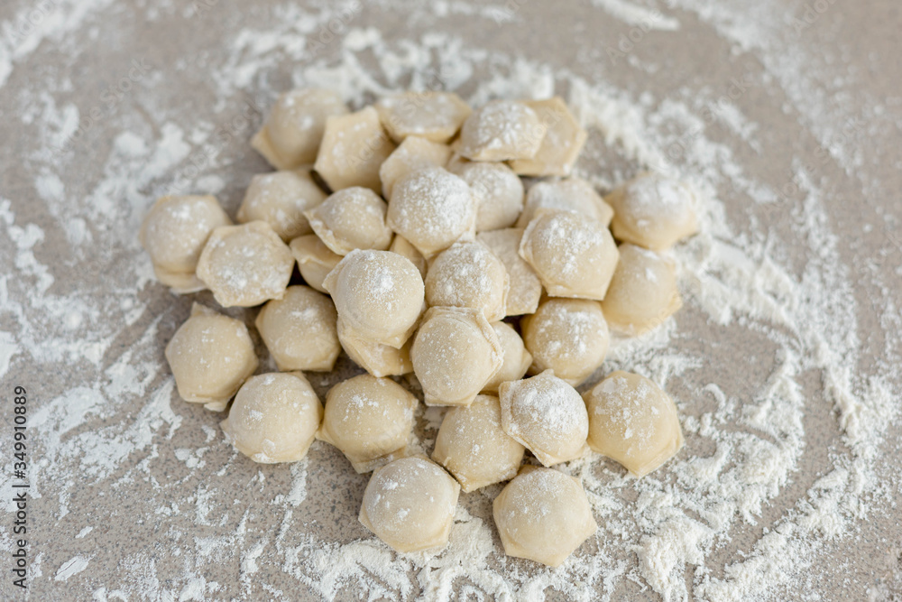Homemade dumplings close-up.  Dumplings lie on a table sprinkled with flour.  A lot of dumplings in bulk