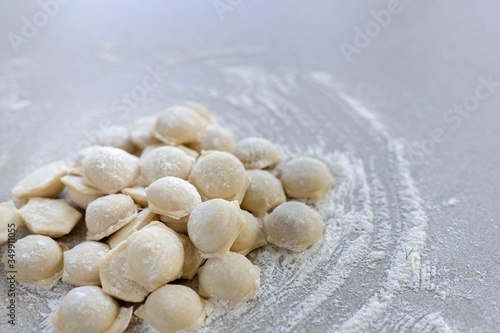 Homemade dumplings close-up. Dumplings lie on a table sprinkled with flour. A lot of dumplings in bulk