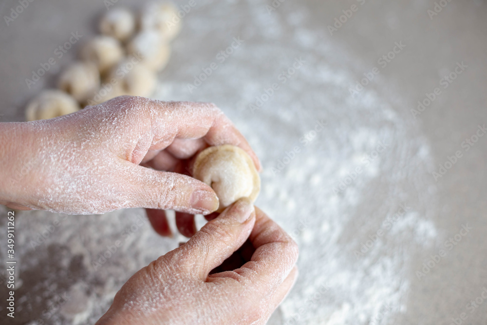 Woman sculpts homemade dumplings bear ears in the kitchen. Modeling dumplings closeup. Female hands sculpt dumplings.