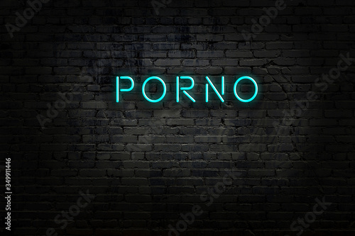 Neon sign with inscription porno against brick wall photo