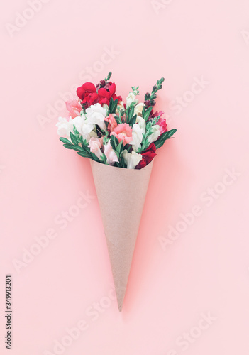 Roses bouquet in cone on pink background, flat lay, top view.
