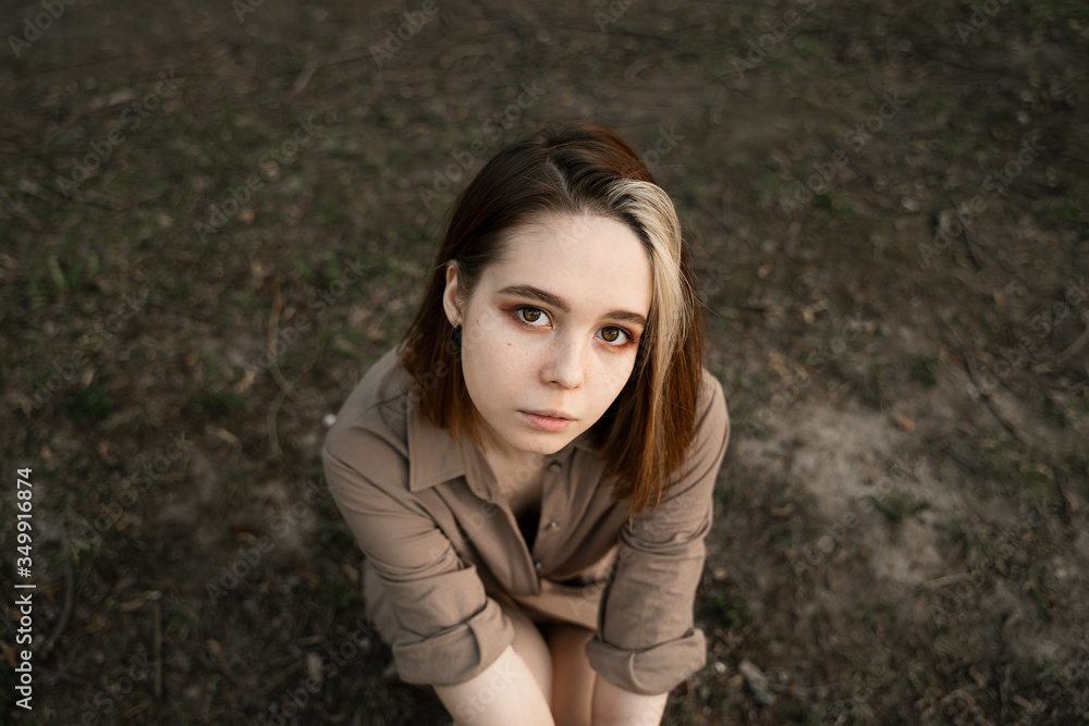 girl sitting on the grass looking directly at the camera girl sitting on the grass looking directly at the camera
