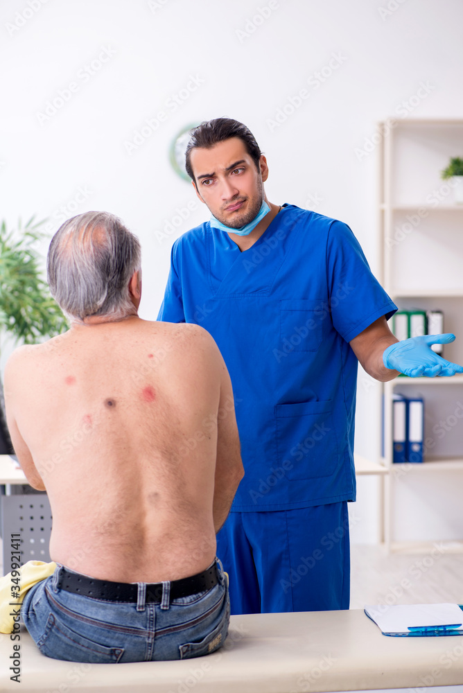 Obraz premium Old man visiting young male doctor dermatologist
