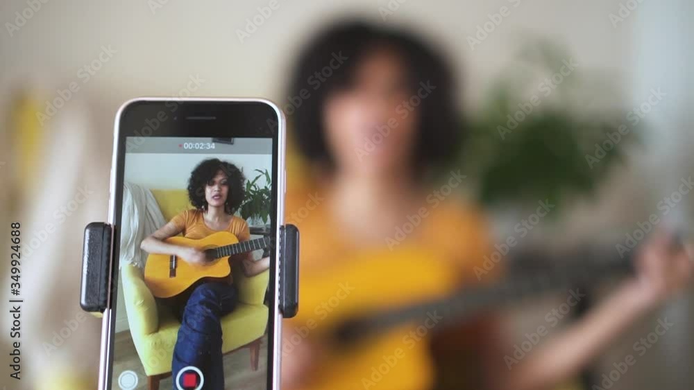 young woman at home singing and playing guitar for followers Spbd. filming blog about learning to sing popular songs. cover, smartphone, recording. confident singer performer young woman at home singing and playing guitar for followers Spbd. filming blog about learning to sing popular songs. cover, smartphone, recording. confident singer performer