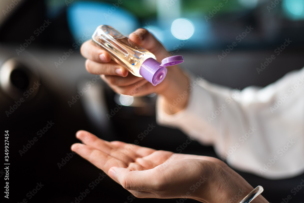 Woman using hand sanitizer in the car for hands disinfection while outdoors