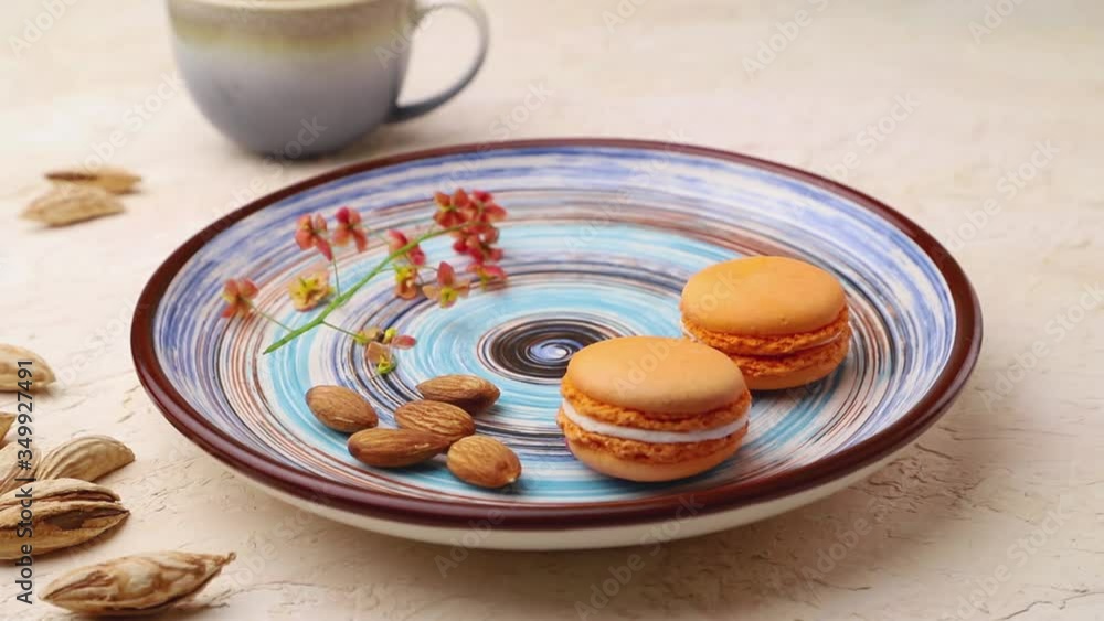 male hand picks macaroons from a ceramic plate on a white concrete background and. Side view, close up. male hand picks macaroons from a ceramic plate on a white concrete background and. Side view, close up.