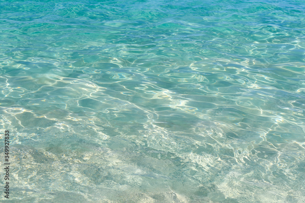 Very clear water plays with sun glare on small waves. Ocean in clear calm weather.Abstract. Background. Very clear water plays with sun glare on small waves. Ocean in clear calm weather.Abstract. Background.