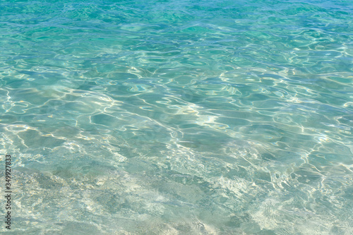 Very clear water plays with sun glare on small waves. Ocean in clear calm weather.Abstract. Background.