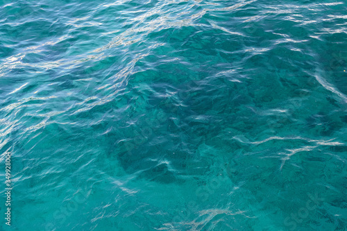 Transparent sea wave of azure color. The seabed shines through clear water. Abstract. Background.