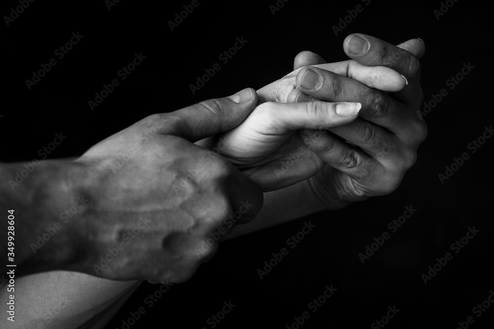 a man holds a woman's hand in his own against a dark background. close up. black and white photo a man holds a woman's hand in his own against a dark background. close up. black and white photo