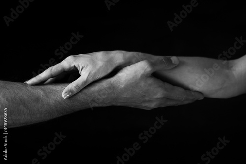 male and female hands touch each other on a dark background. close up. black and white photo