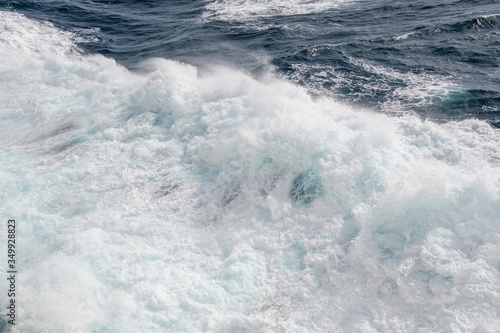 Ocean wave with a dense cap of sea foam in stormy weather. Background. Abstract.