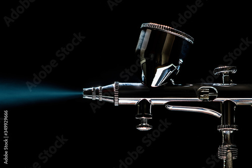 Precision painting with Airbrush using blue color by black background where the pressure is provided by a hobby compressor