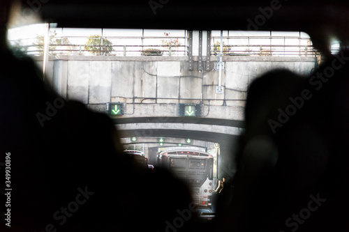 Abstract closeup back of people sitting in bus on trip tourist travel with urban view through window of New York City, NYC highway road tunnel arrows