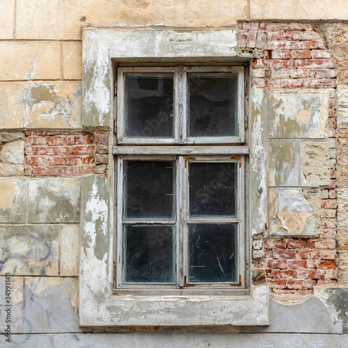 Old vintage window in a white wooden frame on a grunge damaged wall.