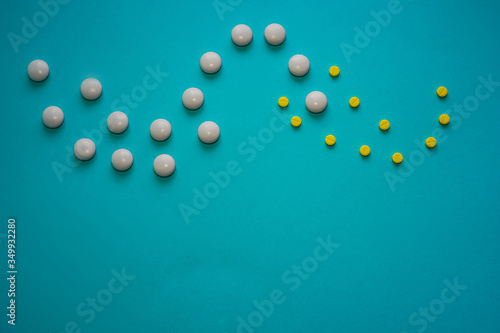 Yellow and white pills on a blue background from above