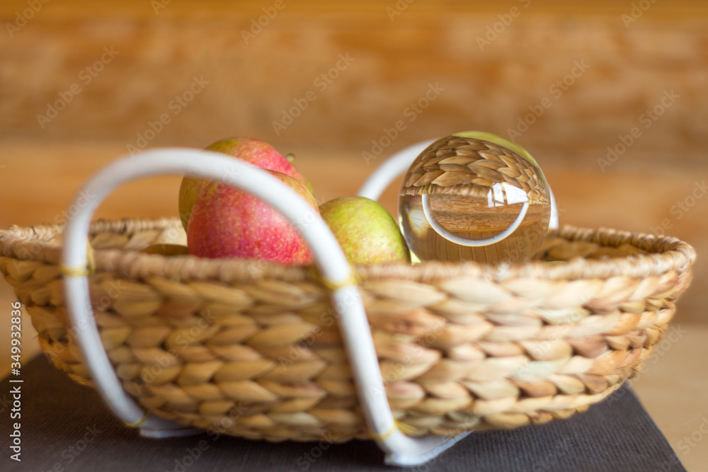 Apples and a glass bowl in a wicker basket. Reflection smile. The decor in the house. Fresh and clean shades. Close-up.