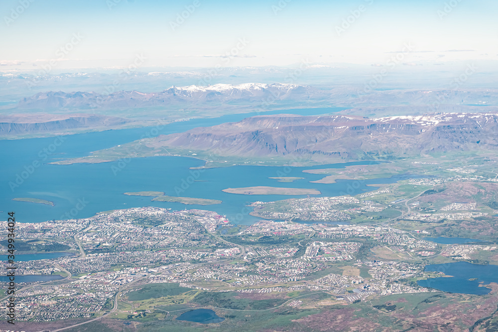 Iceland urban city bird's eye aerial high angle view of Reykjavik from airplane window above and snowcapped mountains Iceland urban city bird's eye aerial high angle view of Reykjavik from airplane window above and snowcapped mountains