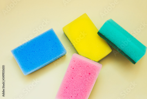 Colorful sponges for washing dishes on yellow background. Artificial fiber not eco-friendly tool. Things for kitchen.