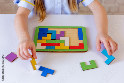 The child collects a puzzle, a constructor of colored parts, and Tetris. Large hands. The process of building the constructor. On light background