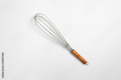 Clean new steel whisk isolated on white background. Cooking egg beater mixer whisker with wooden handle. High-resolution photo.