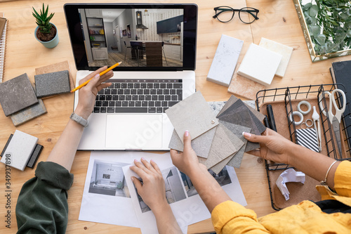 Contemporary designer pointing at home interior example on laptop display photo