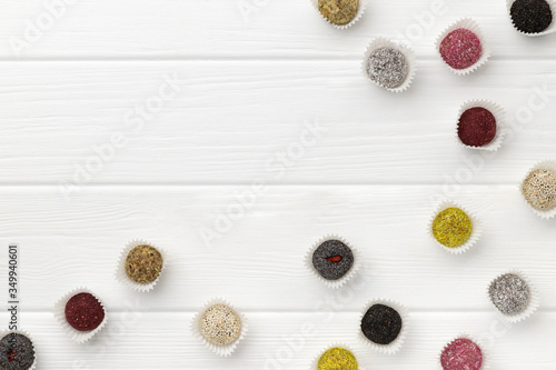 Many colorful vegan candies energy balls on white wooden table
