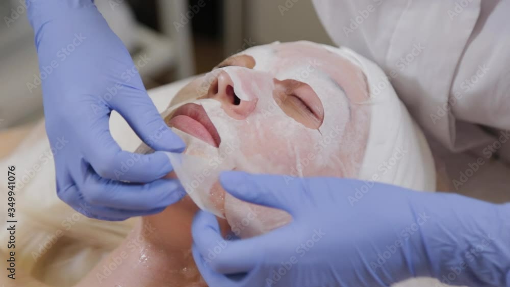 Professional puts face mask to woman client. Cosmetology. Professional puts face mask to woman client. Cosmetology.