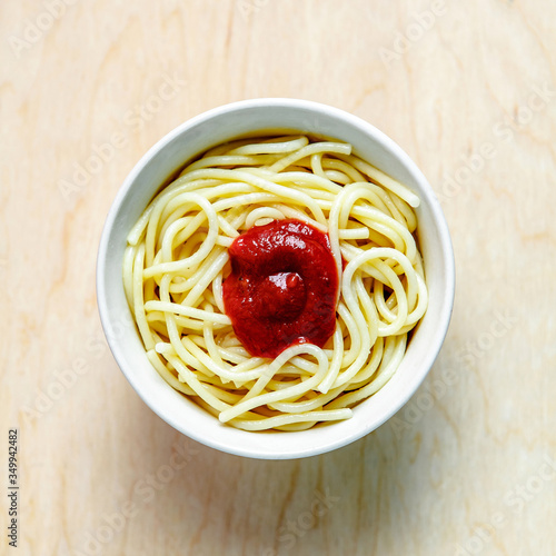 spaghetti in a white plate on a wooden board 
with ketchup