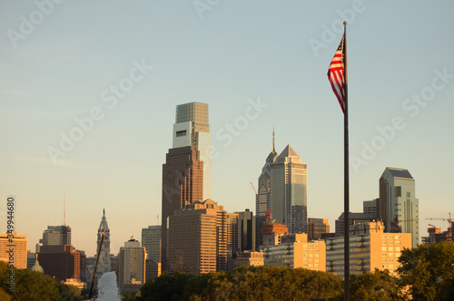 The American flag hangs on a pole in front of the Philadelphia skyline on a sunny evening