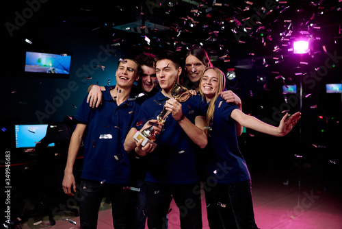 Group of five teenagers celebrating their victory in cybersports competition
