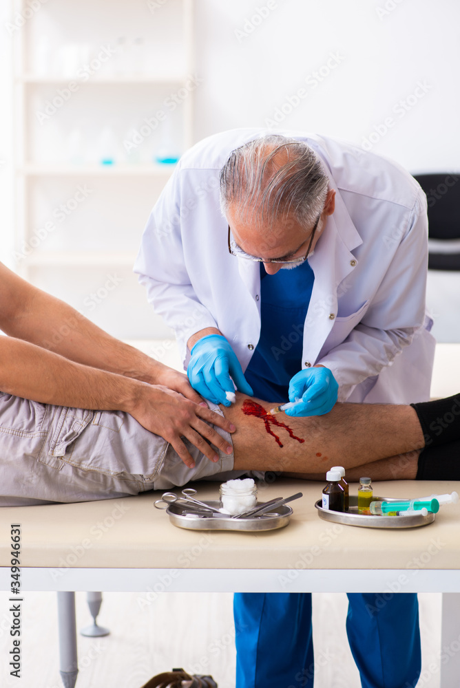Leg injured man visiting old doctor in first aid concept Leg injured man visiting old doctor in first aid concept