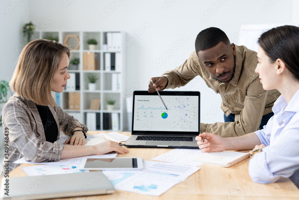 Confident young businessman of African ethnicity looking at one of colleagues Confident young businessman of African ethnicity looking at one of colleagues