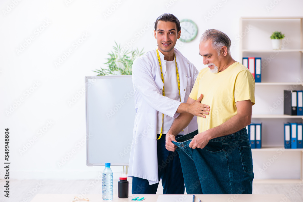 Fototapeta premium Doctor dietician and happy patient wearing large trousers