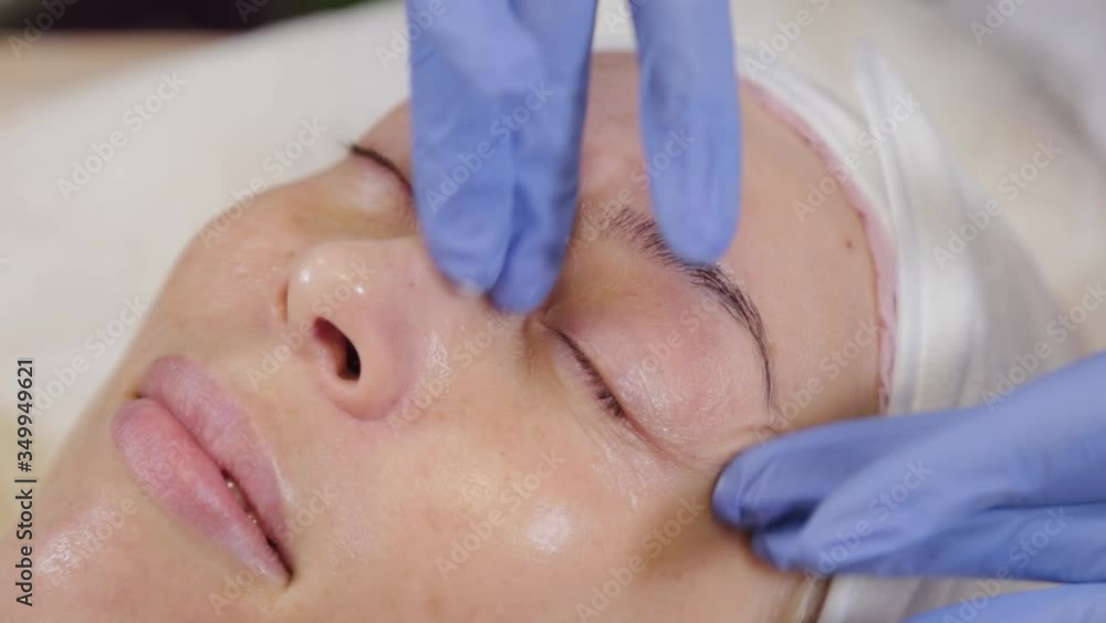 Professional applies cream to the face of a woman client. Cosmetology. Professional applies cream to the face of a woman client. Cosmetology.