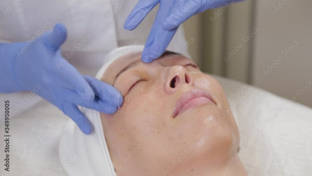 Professional applies cream to the face of a woman client. Cosmetology. Professional applies cream to the face of a woman client. Cosmetology.