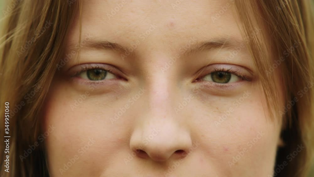 Natural beauty concept. Close up shot of caucasian woman with beautiful green eyes and frekles blinking and smiling Natural beauty concept. Close up shot of caucasian woman with beautiful green eyes and frekles blinking and smiling