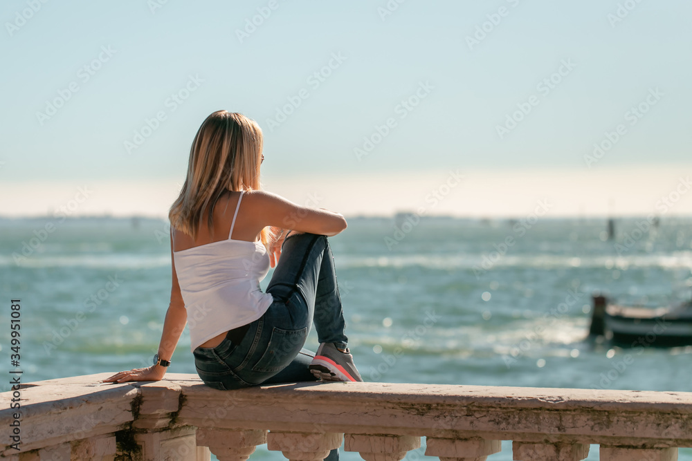 A portrait of woman relaxing on the traditional meditteranean balcony edge looking over the sea