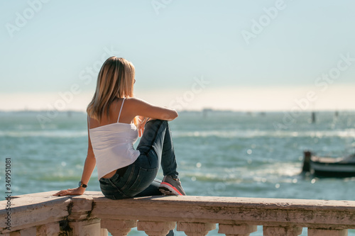 A portrait of woman relaxing on the traditional meditteranean balcony edge looking over the sea © Milena