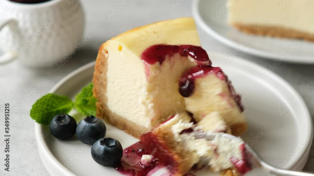 Eating cheesecake with blueberry sauce. Taking bite of cheesecake with fork. Tasty dessert cream cake Eating cheesecake with blueberry sauce. Taking bite of cheesecake with fork. Tasty dessert cream cake