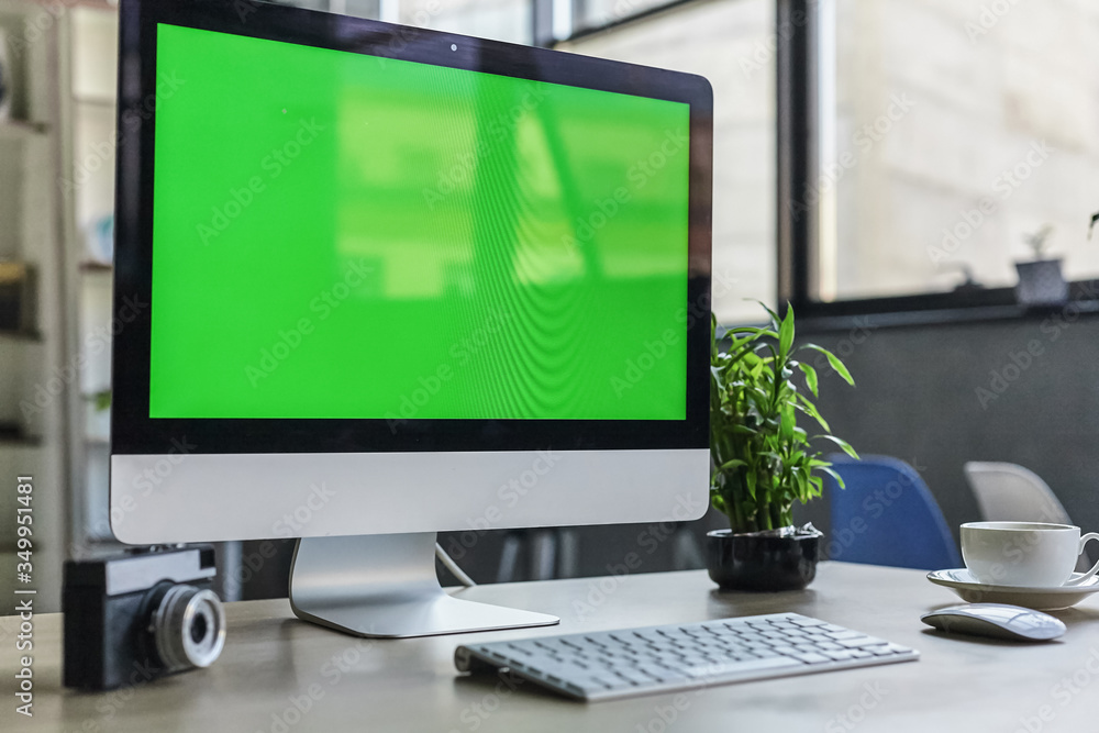 Computer desktop with mock-up green screen white background in office and Lovely plant in black pot Computer desktop with mock-up green screen white background in office and Lovely plant in black pot