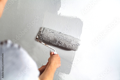 Wallpaper Mural Human hand with large roller of paint begins to paint a white wall handicraft master painter training contrast color sample color test tool renovation gray silver craftsman Torontodigital.ca