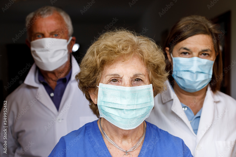 gruppo di tre medici esperti con mascherina e camice bianco che guardano decisi, isolati su sfondo nero gruppo di tre medici esperti con mascherina e camice bianco che guardano decisi, isolati su sfondo nero