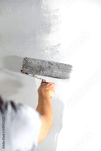 Wallpaper Mural Human hand with large roller of paint begins to paint a white wall handicraft master painter training contrast color sample color test tool renovation gray silver craftsman Torontodigital.ca