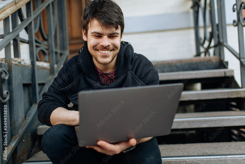 Young male working on his laptop computer in the city center. An independent person typing something in his document. chatting with friends over the internet, webcam Young male working on his laptop computer in the city center. An independent person typing something in his document. chatting with friends over the internet, webcam