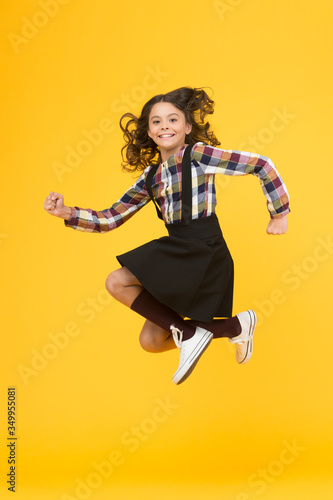 Fototapeta Naklejka Na Ścianę i Meble -  Day full of fun. Happy child enjoy happiness. Energetic girl in midair yellow background. Childhood and happiness. School holidays. Free time. Happiness concept. Happiness is habit