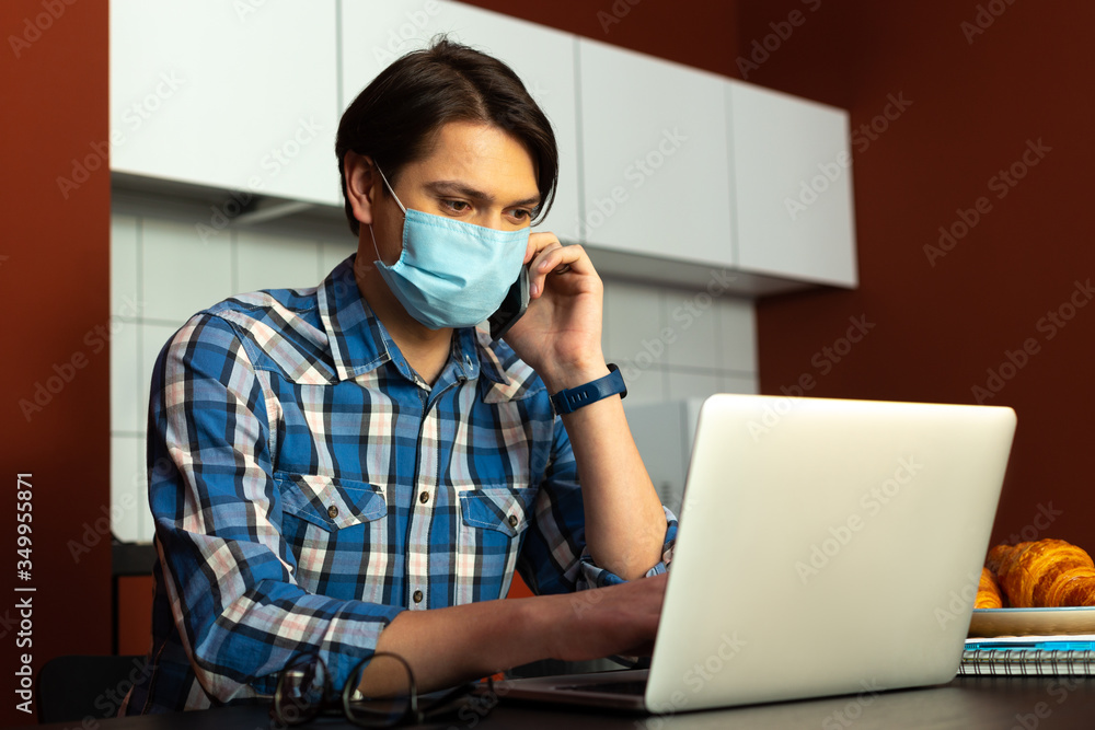 Man in sterile mask with gadgets in kitchen Man in sterile mask with gadgets in kitchen